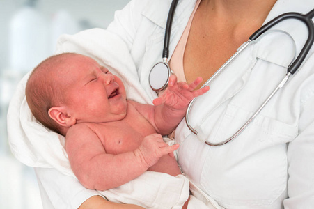 儿科医生用听诊器把新生儿抱在怀里