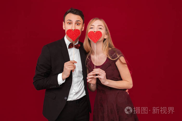 一对幸福的夫妻在红色背景情侣日捧着纸心的画像