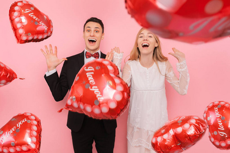 一对相爱的夫妇一男一女在一间粉色背景的工作室里拿着心形气球