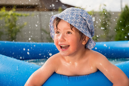 微笑的男孩带着水滴在游泳池里消磨时间. 玩水. 阳光明媚的夏天.