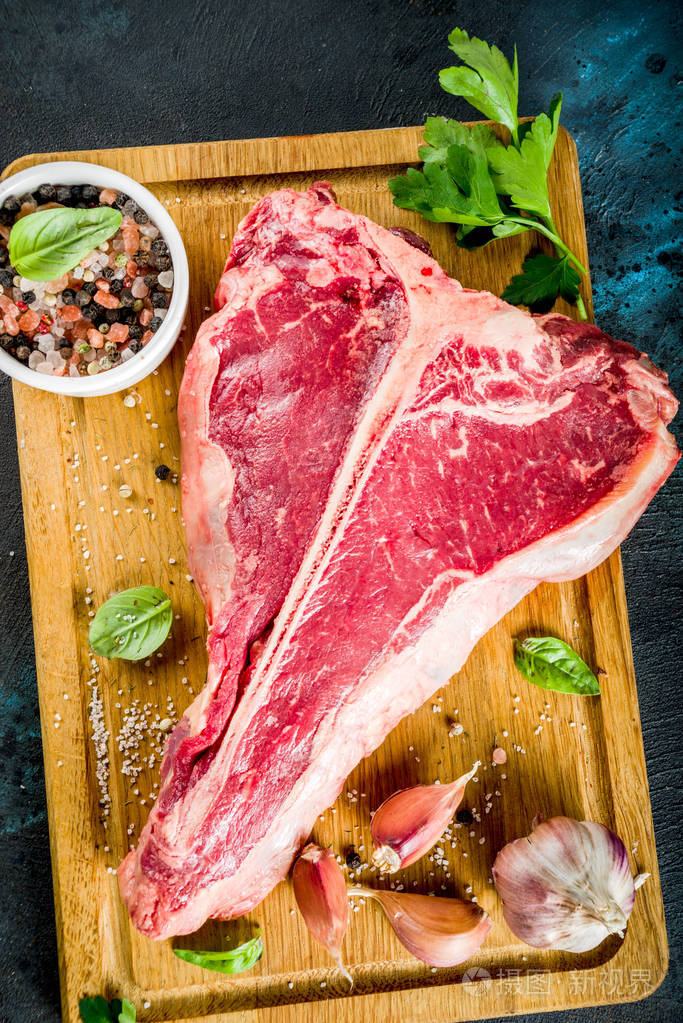 生鲜肉t骨牛排加香料和草药在切割板混凝土桌面上看到