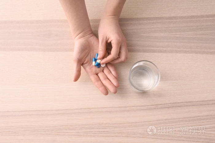 年轻女子在餐桌上吃药片照片-正版商用图片16kkiq-摄图新视界
