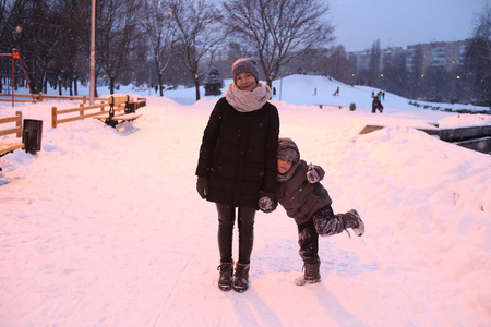 家庭妈妈带着孩子在公园外面玩冬天的雪季快乐