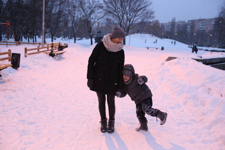 家庭妈妈带着孩子在公园外面玩冬天的雪季快乐