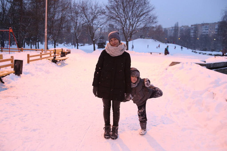 家庭妈妈带着孩子在公园外面玩冬天的雪季快乐