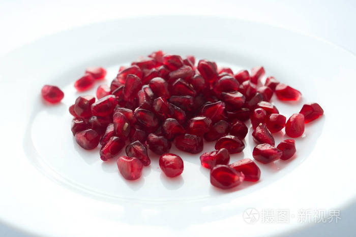 白色背景的白色盘子上的红色石榴颗粒