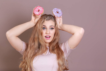 有趣的年轻女子与美味的甜甜圈的颜色背景
