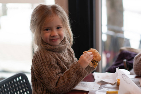 小女孩在咖啡馆里吃汉堡