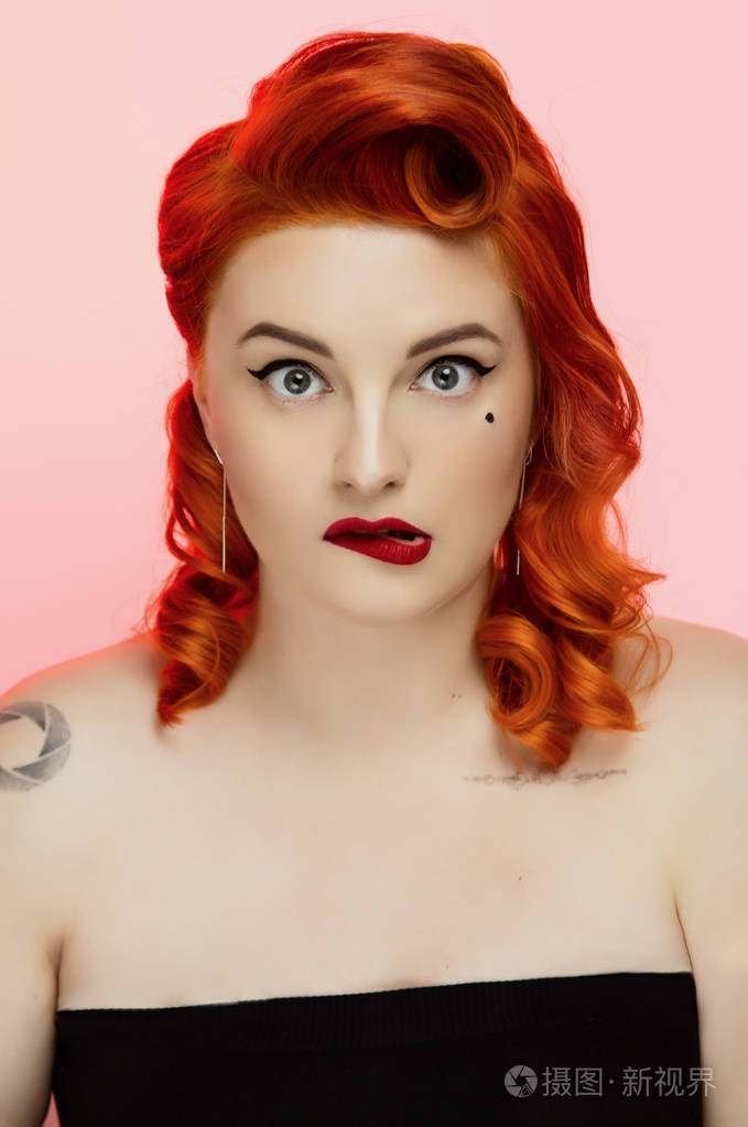 一个美丽的红发女孩的肖像,用别针化妆和头发在工作室的颜色背景情感