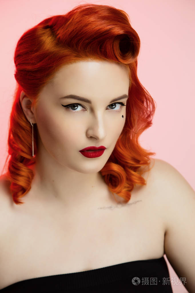 一个美丽的红发女孩的肖像,用别针化妆和头发在工作室的颜色背景情感