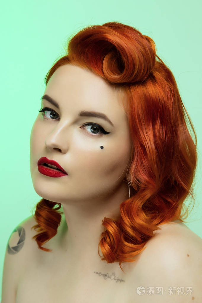 一个美丽的红发女孩的肖像,用别针化妆和头发在工作室的颜色背景情感