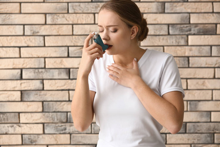 吸入剂的年轻女性哮喘发作于砖墙
