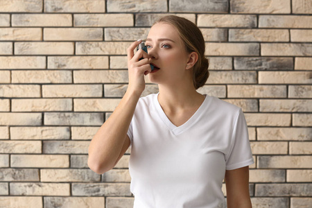 吸入剂的年轻女性哮喘发作于砖墙