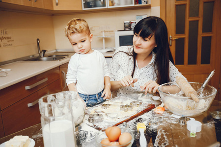 一位穿着白衬衫的年轻母亲正和她的小儿子一起在家厨房准备食物