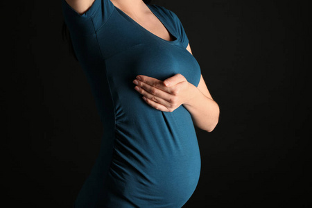 孕妇哺乳孕妇在黑暗的背景下抚摸乳房照片