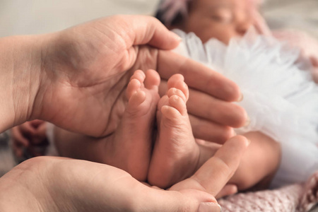 s hands holding tiny feet of little baby, closeup