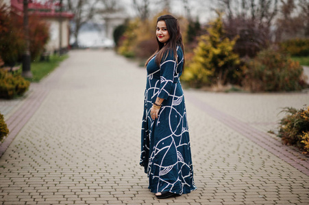 深色印度女人穿着长而时尚的裙子在户外摆姿势。