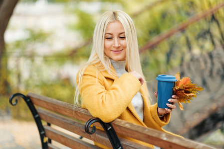 年轻时尚的金发女人喝咖啡去公园