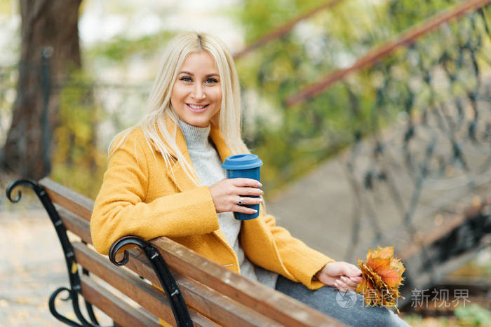 年轻时尚的金发女人喝咖啡去公园