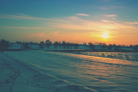 冬天的雪景。 在白雪覆盖的田野上日落