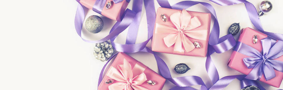 横幅圣诞盒与礼物的粉红色的白色背景锥螺母装饰。 平视平视水平选择性聚焦