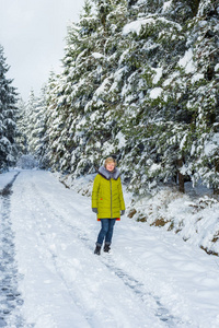 一个年轻的女人正在白雪覆盖的树木之间穿过冬林