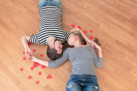 最爱的年轻夫妇躺在地板上互相看着对方。 色调空的地方。