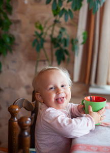 可爱的小女孩在杯子里喝茶