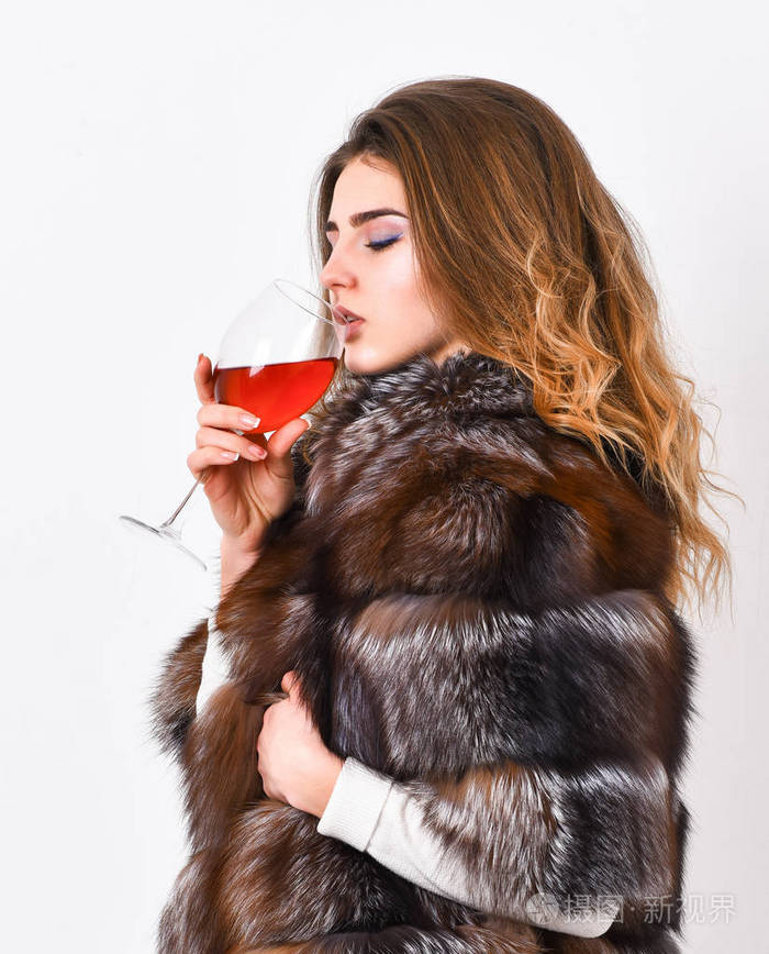 冬天喝红酒的原因.女人喝酒.女孩时尚化妆穿皮大衣举行玻璃酒精.