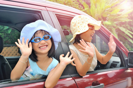 微笑快乐的亚洲小孩在车上挥舞双手手上的动作，旅行概念