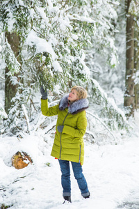 一个年轻的女人正在白雪覆盖的树林间穿过冬林