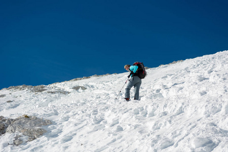 女性登山运动员登上陡峭的雪坡