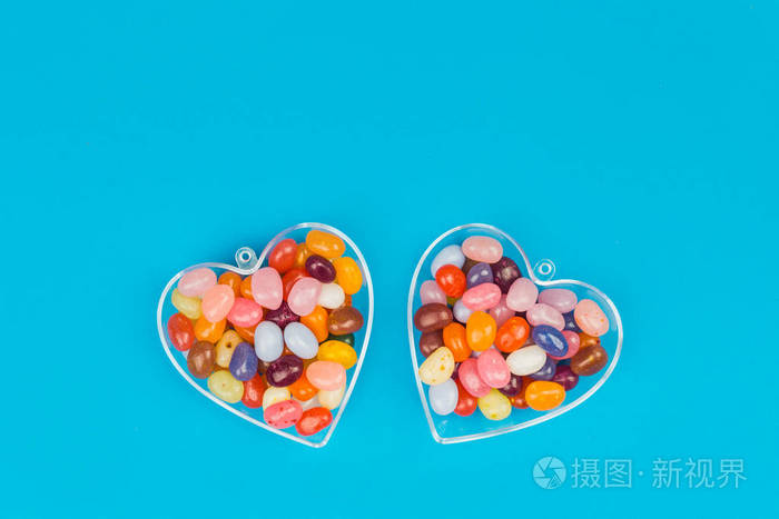 两颗心与彩色糖果在蓝色背景平躺与复制空间爱与情人节的概念