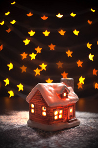圣诞作文。 玩具屋在一个黑色背景模糊的离焦多色灯在形式明星。 圣诞节冬季新年概念。