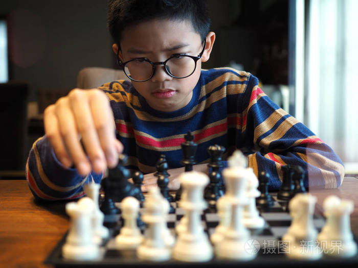 亚洲男孩在家里的桌子上下棋选定的重点