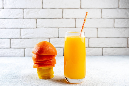白色桌子上有新鲜的橙汁和柠檬汁。 自制柑橘汁。 健康饮食和抗氧化概念