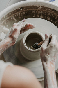 创造一个罐子或花瓶白色粘土关闭。 女人的手在陶工轮上做陶罐。