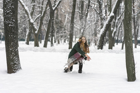 树间公园里的女人朝镜头扔雪球