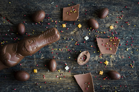 复活节用巧克力蛋兔子和糖果在古老的乡村木制背景上组成。复活节假期快乐。上景。平躺着。