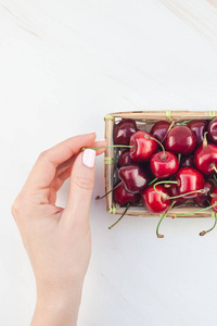 创意顶部的新鲜成熟樱桃在一个小柳条篮子与复制空间孤立的白色背景最小风格。 夏季乐趣和健康饮食的概念。 你的文字或食物设计模板