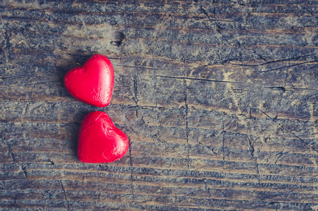 情人节背景与两个红色巧克力心形糖果在一个乡村木桌上与文字的地方.
