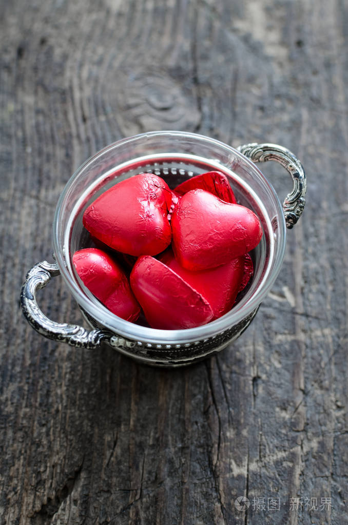 情人节背景与红色巧克力心形糖果在老式碗在一个乡村木制桌子文字的