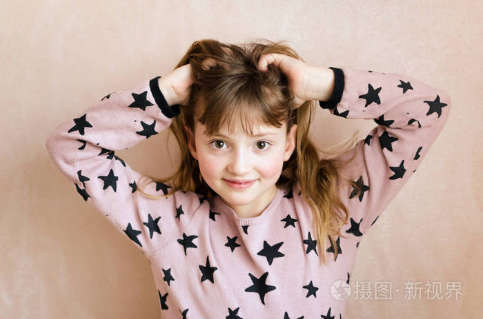 小女孩有一头长长的深色金发在粉红色的背景上有一双美丽的棕色眼睛带