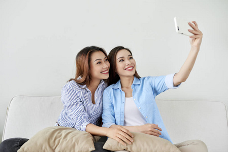 特写两个兴奋的女朋友的肖像，用手机笑。 快乐快乐的女性朋友在家休息，享受谈话的乐趣。