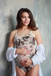 孕妇在阁楼背景上把手放在肚子上。 怀孕产妇准备和期望概念。 关闭室内复制空间。
