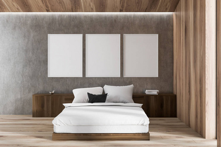 阁楼卧室的内部有木制和灰色的墙壁，木制地板，深色木床，上面有白色的毯子和海报画廊。3D渲染模拟