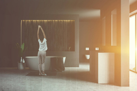 现代浴室的内部有灰色和木制墙壁混凝土地板白色浴缸两个方形水槽和两个厕所。彩色图像双曝光