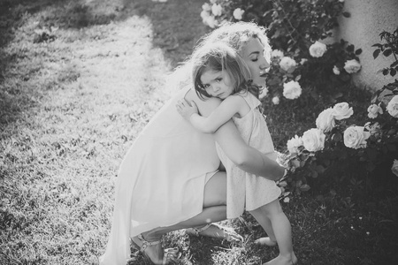 在阳光明媚的夏日, 妈妈抱着女儿在青草上
