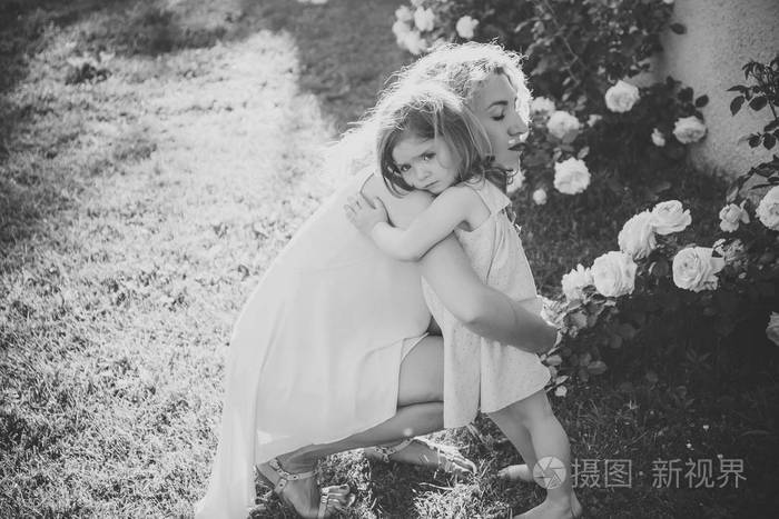 在阳光明媚的夏日妈妈抱着女儿在青草上