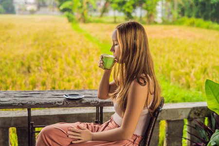 拿着一杯抹茶拿铁, 绿茶, 在老木背景桌上的年轻妇女